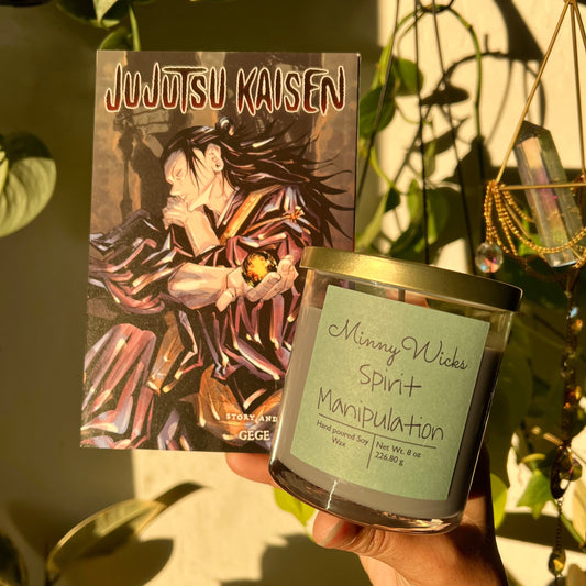 Candle labeled 'Minny Wicks Spirit Manipulation' held next to a 'Jujutsu Kaisen' book